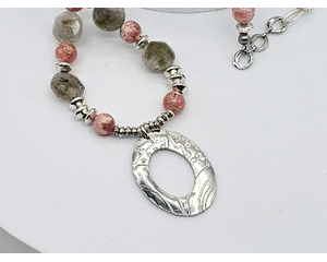 Handcrafted necklace with Rhodochrosite and Labradorite beads, silver accents, and an embossed pewter pendant on a 20-inch strand.